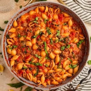 Ground beef pasta in skillet topped with basil.