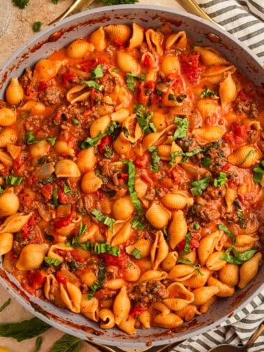 Ground beef pasta in skillet topped with basil.