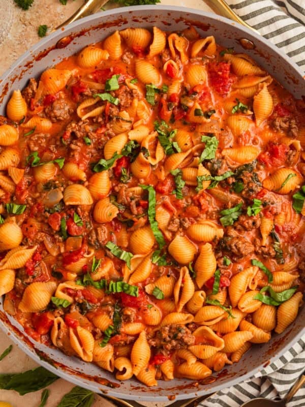 Ground beef pasta in skillet topped with basil.