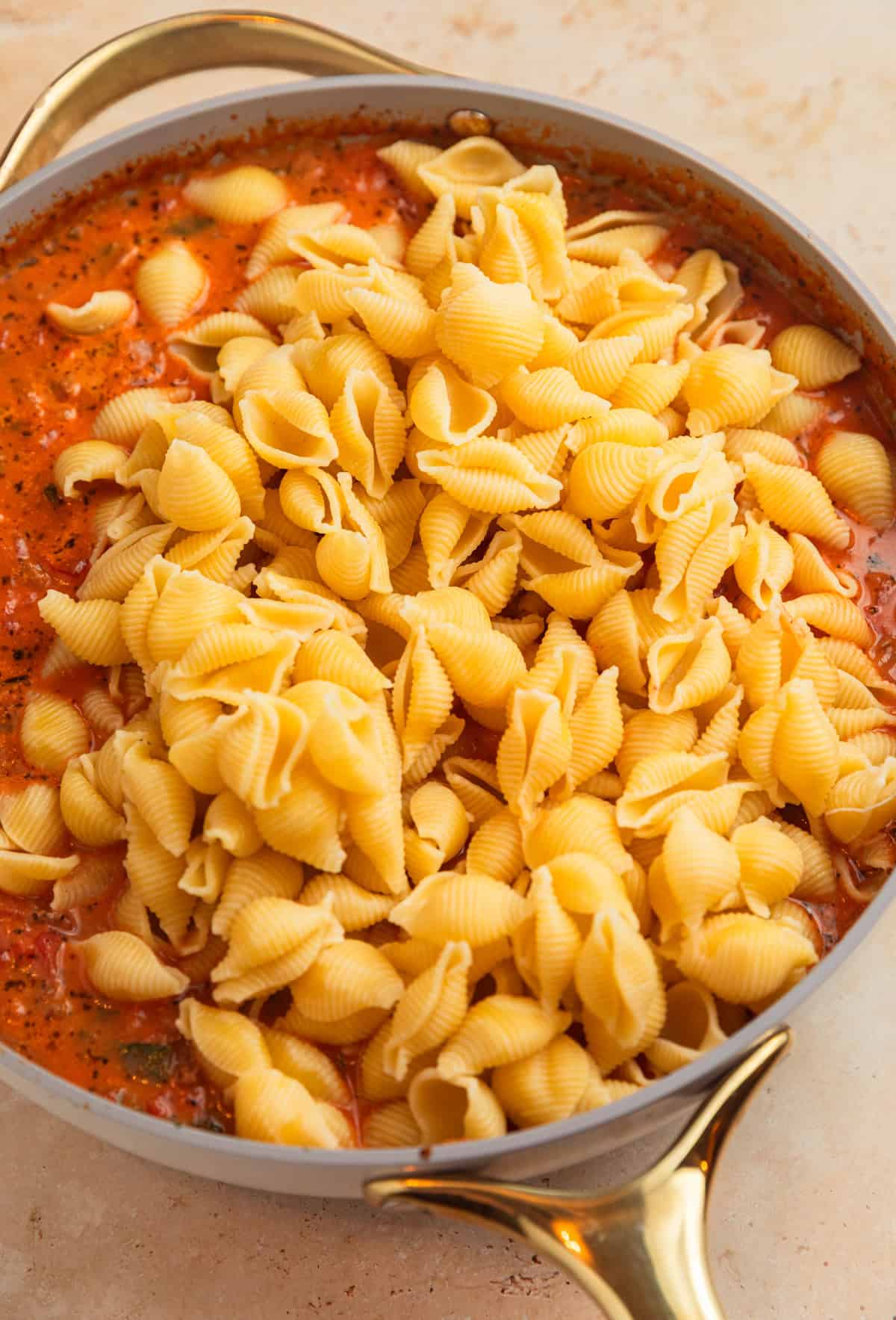 Pasta added to ground beef tomato mixture in pot.
