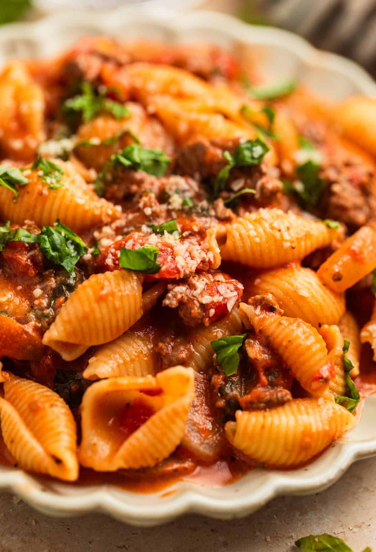 Ground beef pasta in dish with parmesan on top.