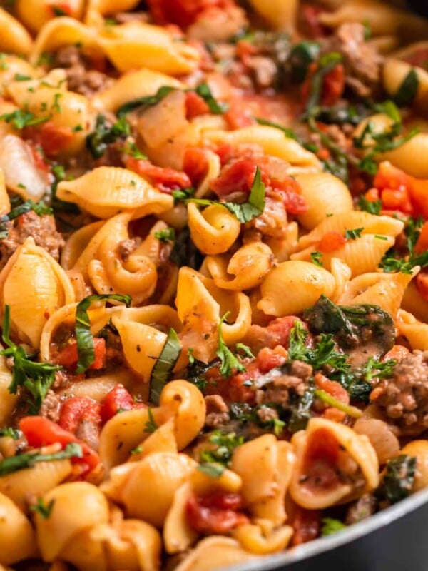 Ground beef pasta recipe in skillet with parsley and basil on top.