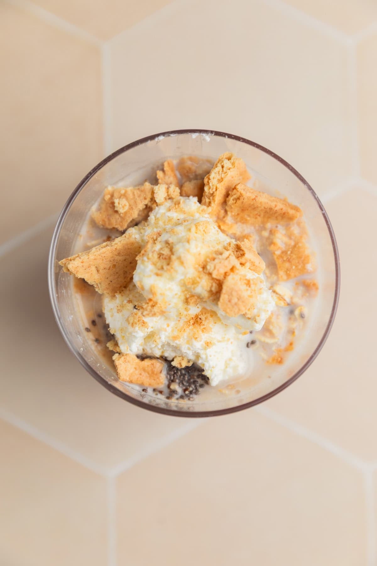 Cup with milk, chia seeds, rolled oats, cream cheese and other ingredients.