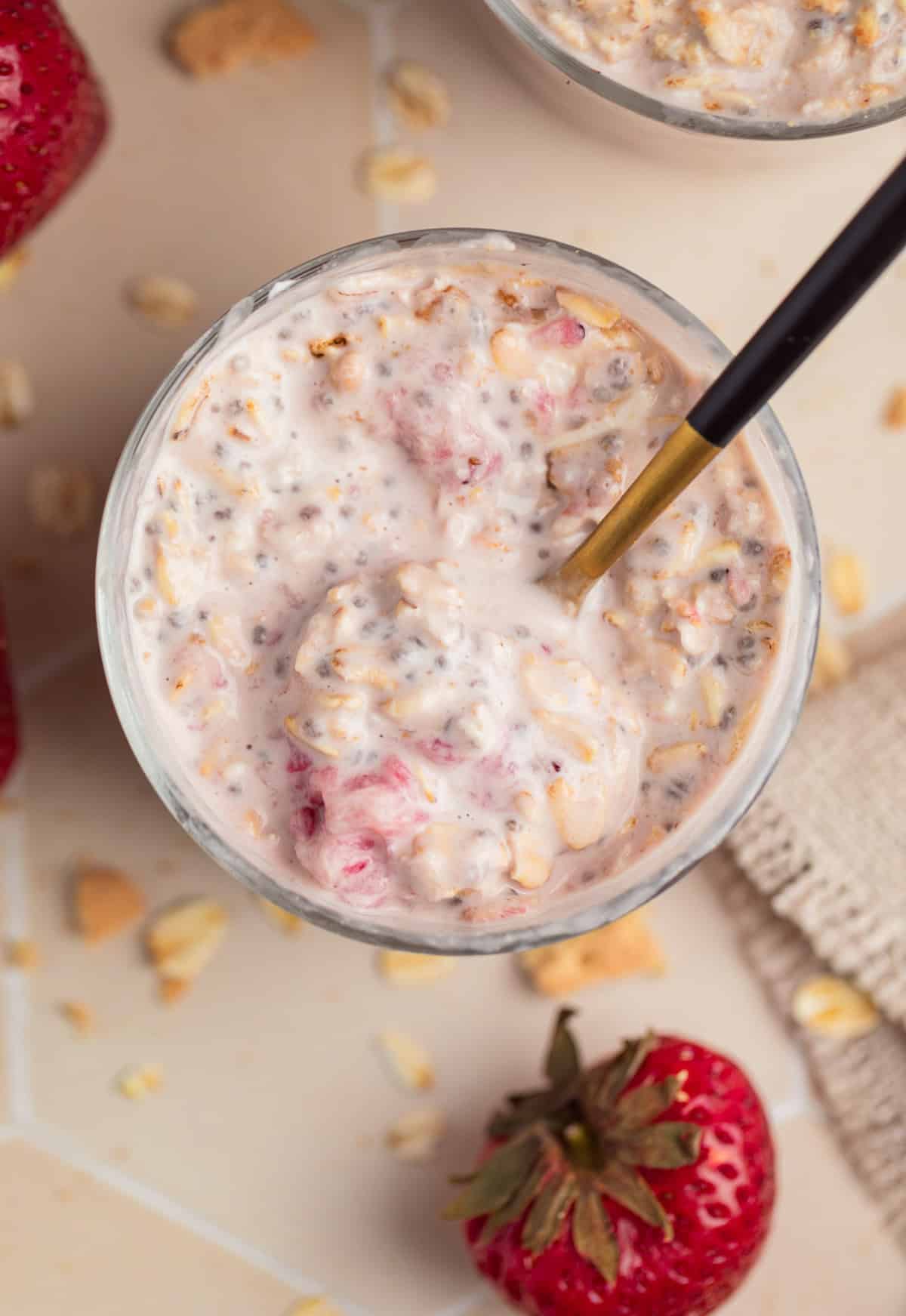 Strawberry cream cheese overnight oatmeal served in glass with spoon.