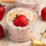 Glass cup with strawberry cheesecake oatmeal with graham crumbs.