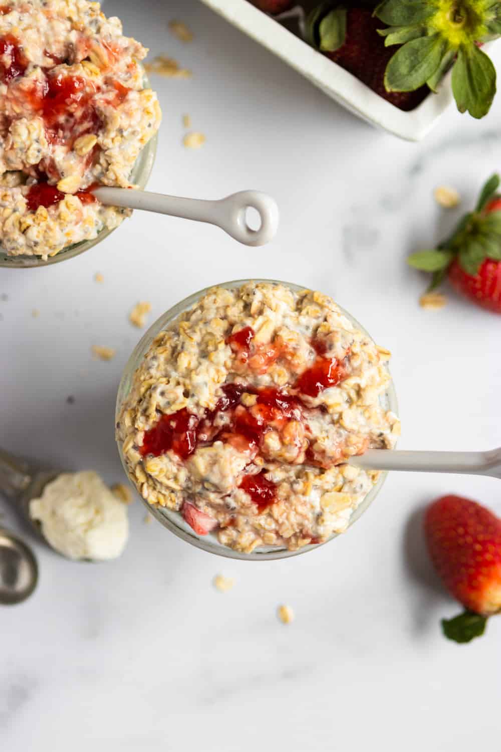 Overhead view of jar of strawberry cheesecake overnight oats with white spoon.