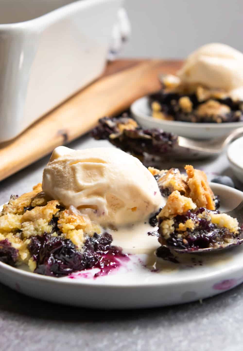 Blueberry dump cake with scoop of vanilla ice cream and spoonful of cake.