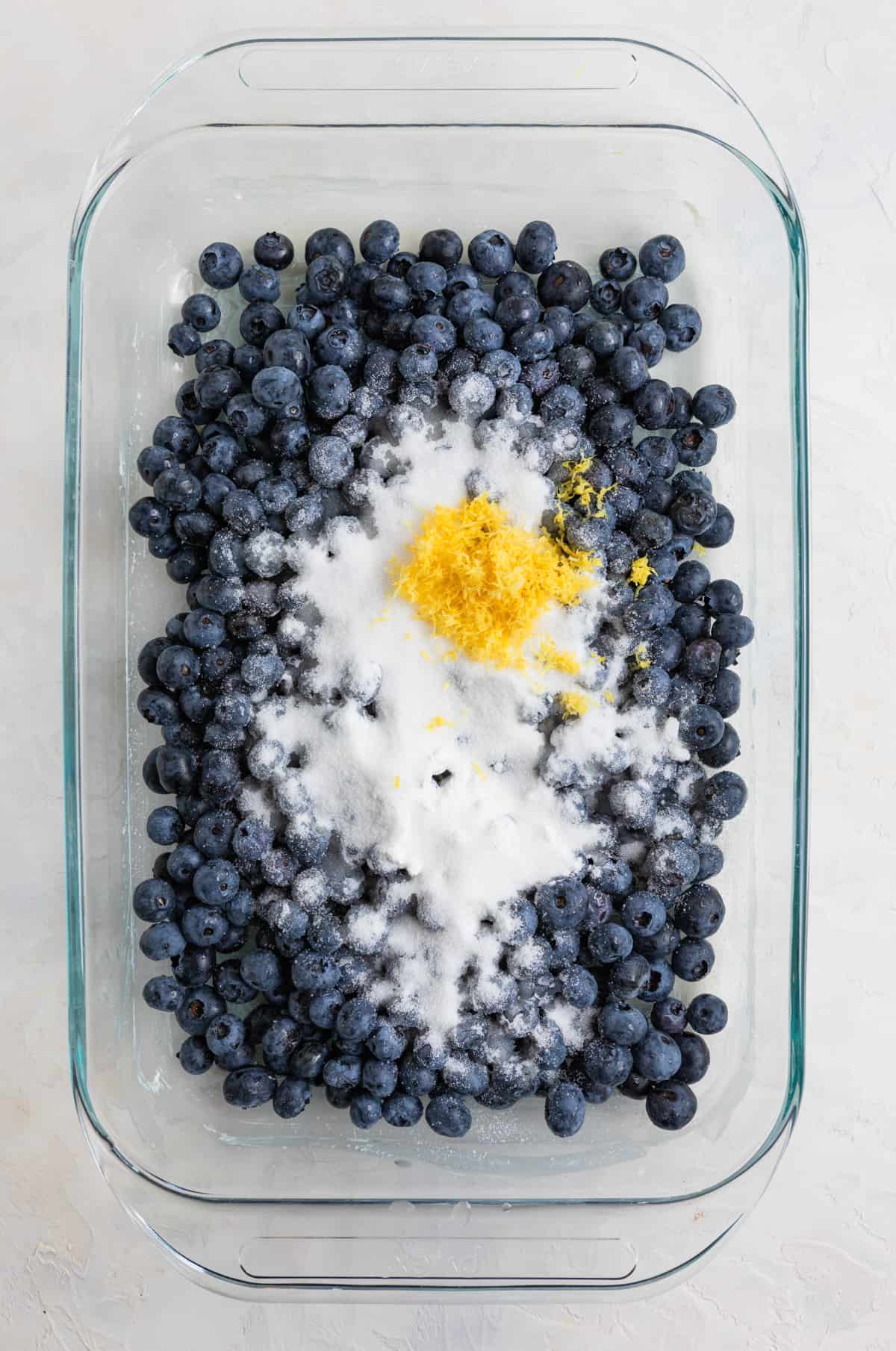 Fresh blueberries, sugar, lemon zest in 9x13 inch glass pan.