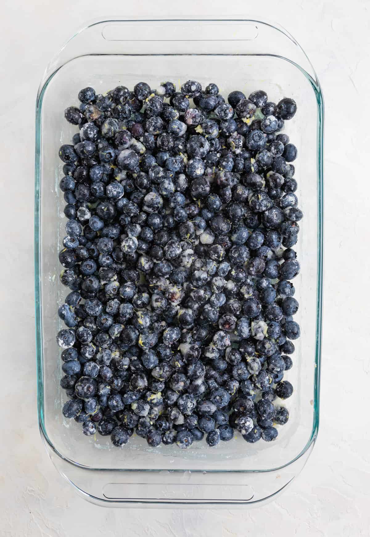 Prepared blueberries in glass baking pan ready for dump cake topping.