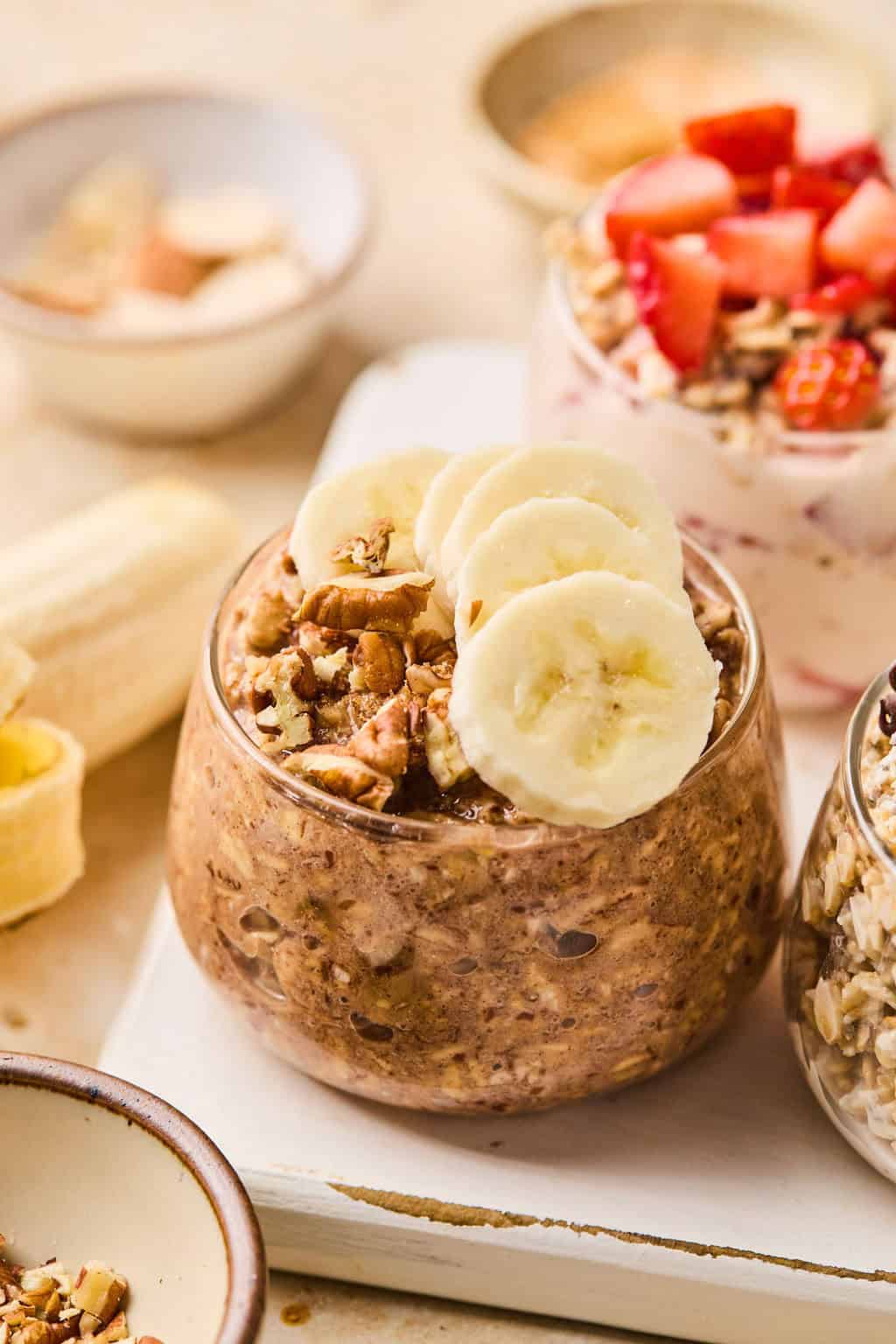 Banana bread overnight oatmeal in glass topped with sliced bananas.