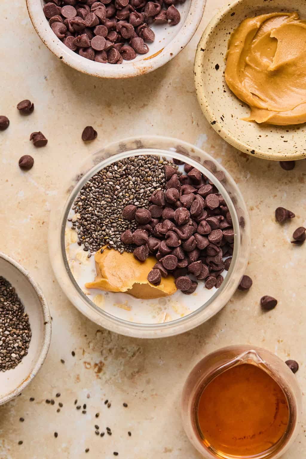 Ingredients for peanut butter chocolate oatmeal arranged on surface with them all added to jar before stirring.