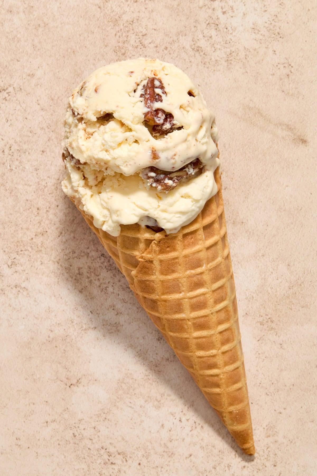 Waffle cone with butter pecan ice cream scooped in.