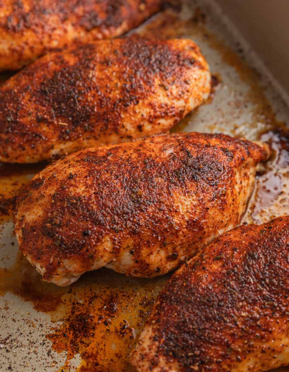 Baked seasoned chicken breasts in baking pan.