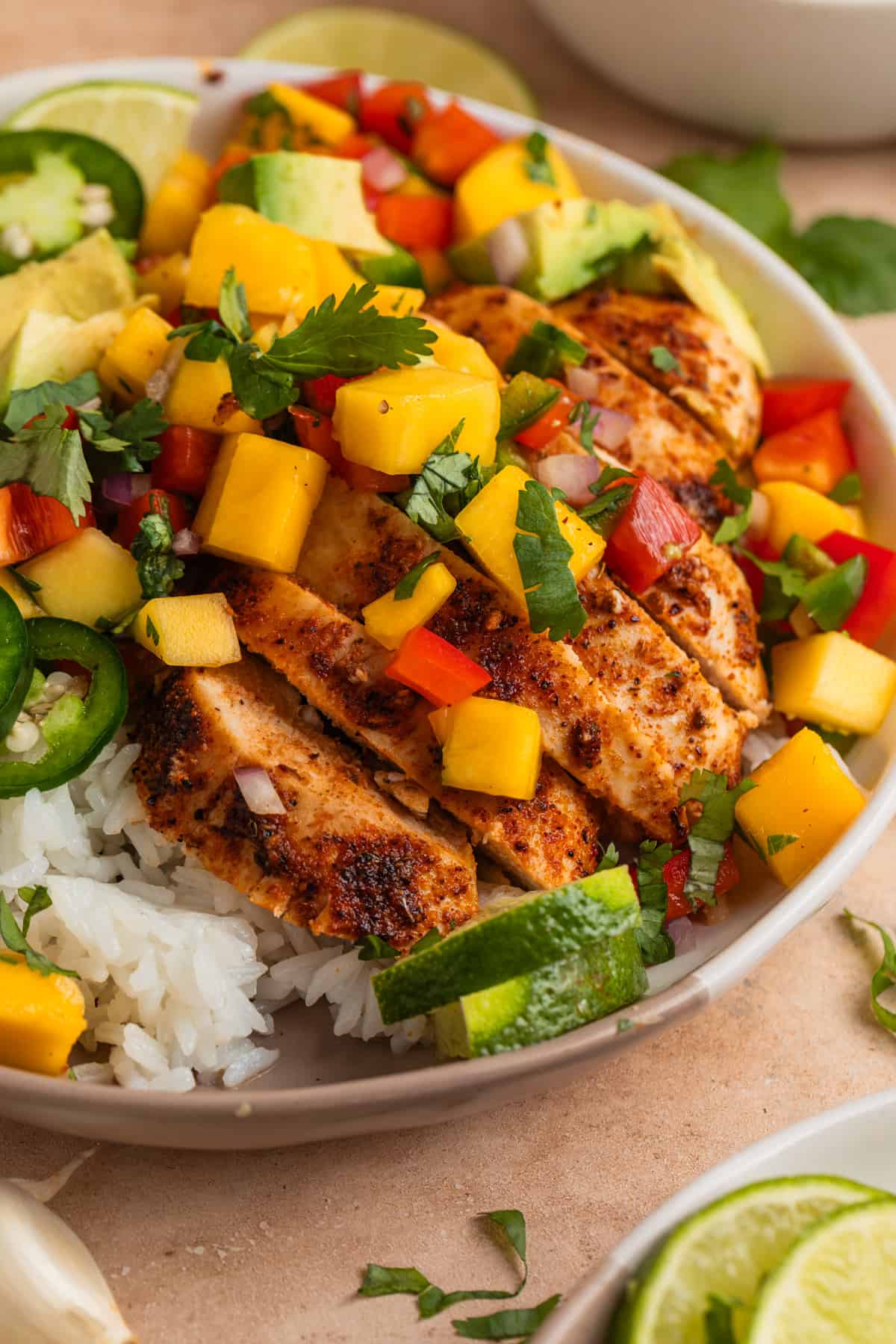 Sliced chicken breast on a bed of rice with mango salsa.