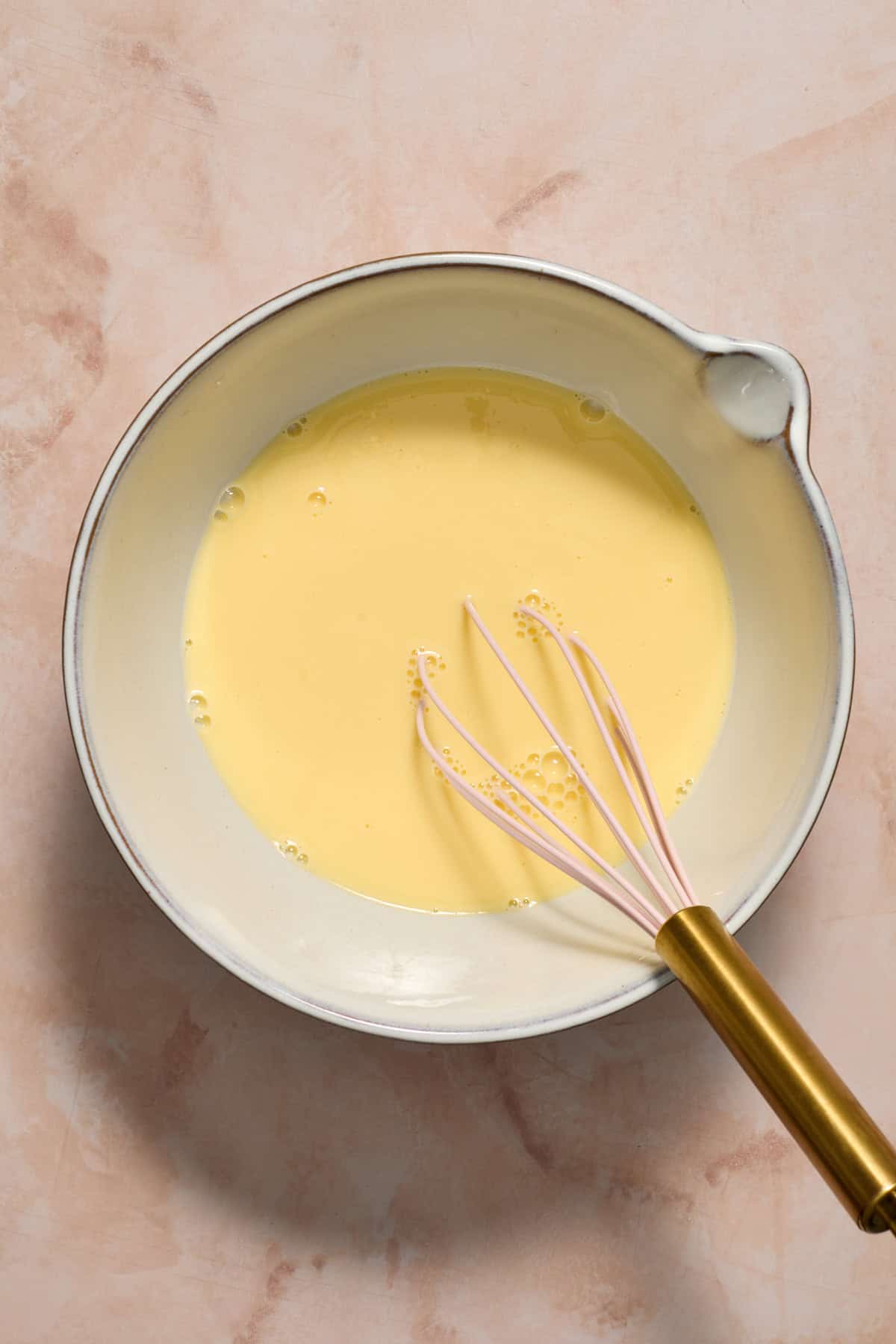 Eggs and milk whisked together in mixing bowl.