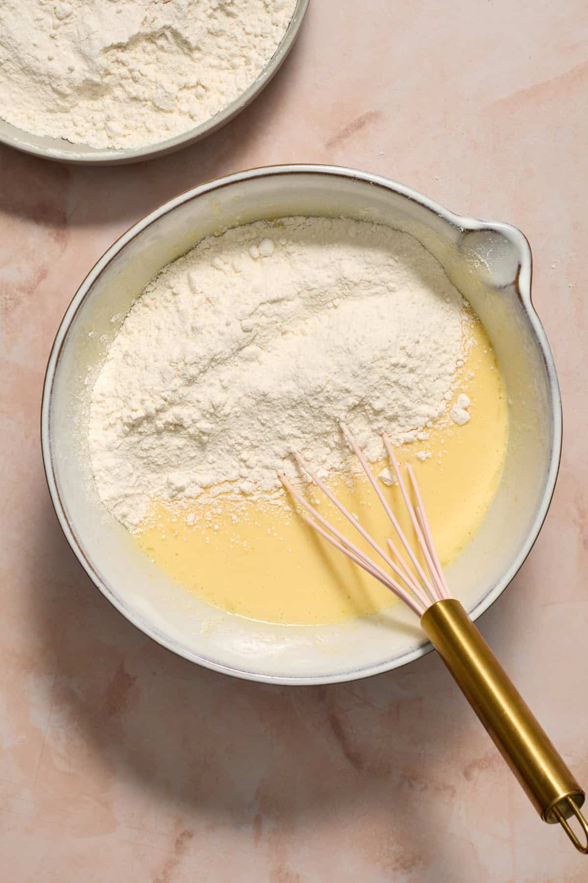 Cake mix added to wet ingredients in bowl with whisk.