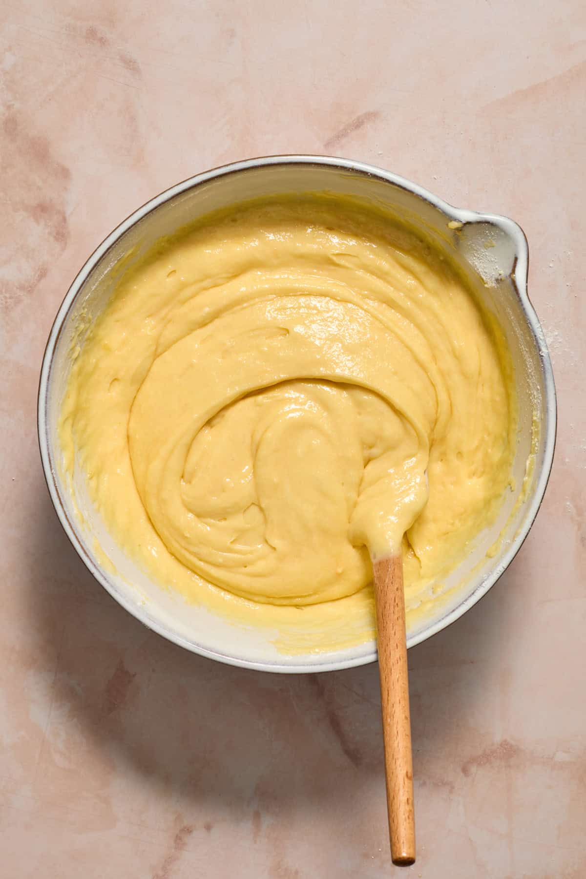 Boxed cake mix batter with extra add-ins and spatula propped in bowl.