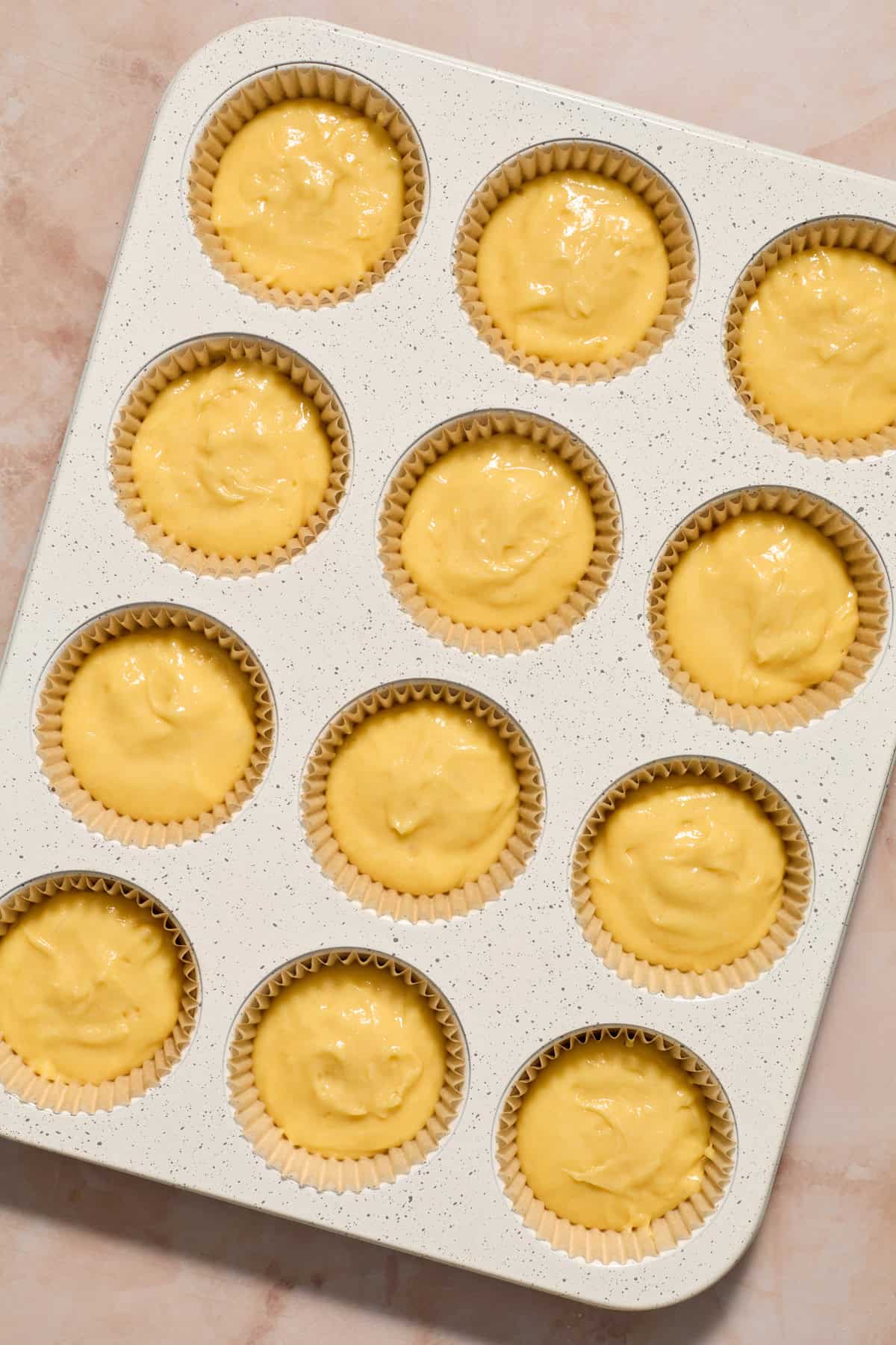 Vanilla cupcake batter in muffin tin before baking.