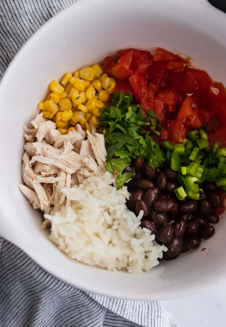 Bowl with recipe ingredients: rice, chicken, corn, cilantro, tomatoes and jalapeño.