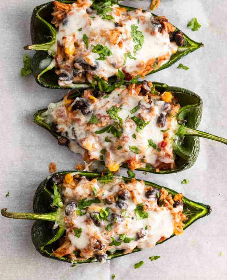 Overhead shot of stuffed peppers on parchment with fresh cilantro.