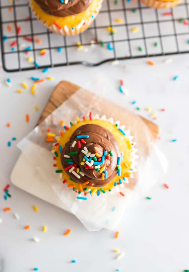 Overhead view of vanilla cupcake with chocolate icing and sprinkles.
