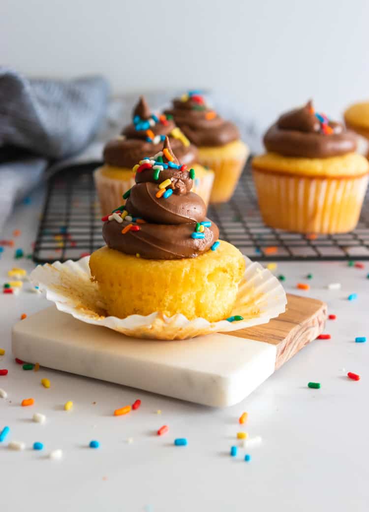 Cupcake with wrapper open around it and sprinkles.