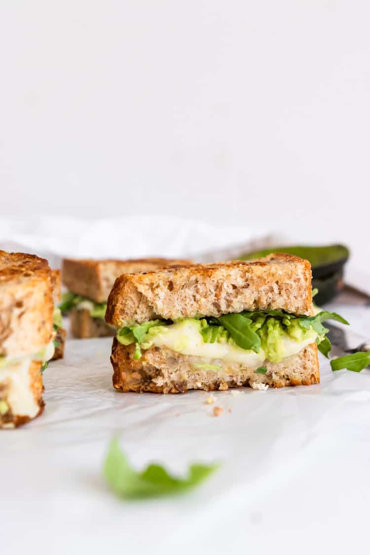 Half of a havarti grilled cheese with avocado and arugula.