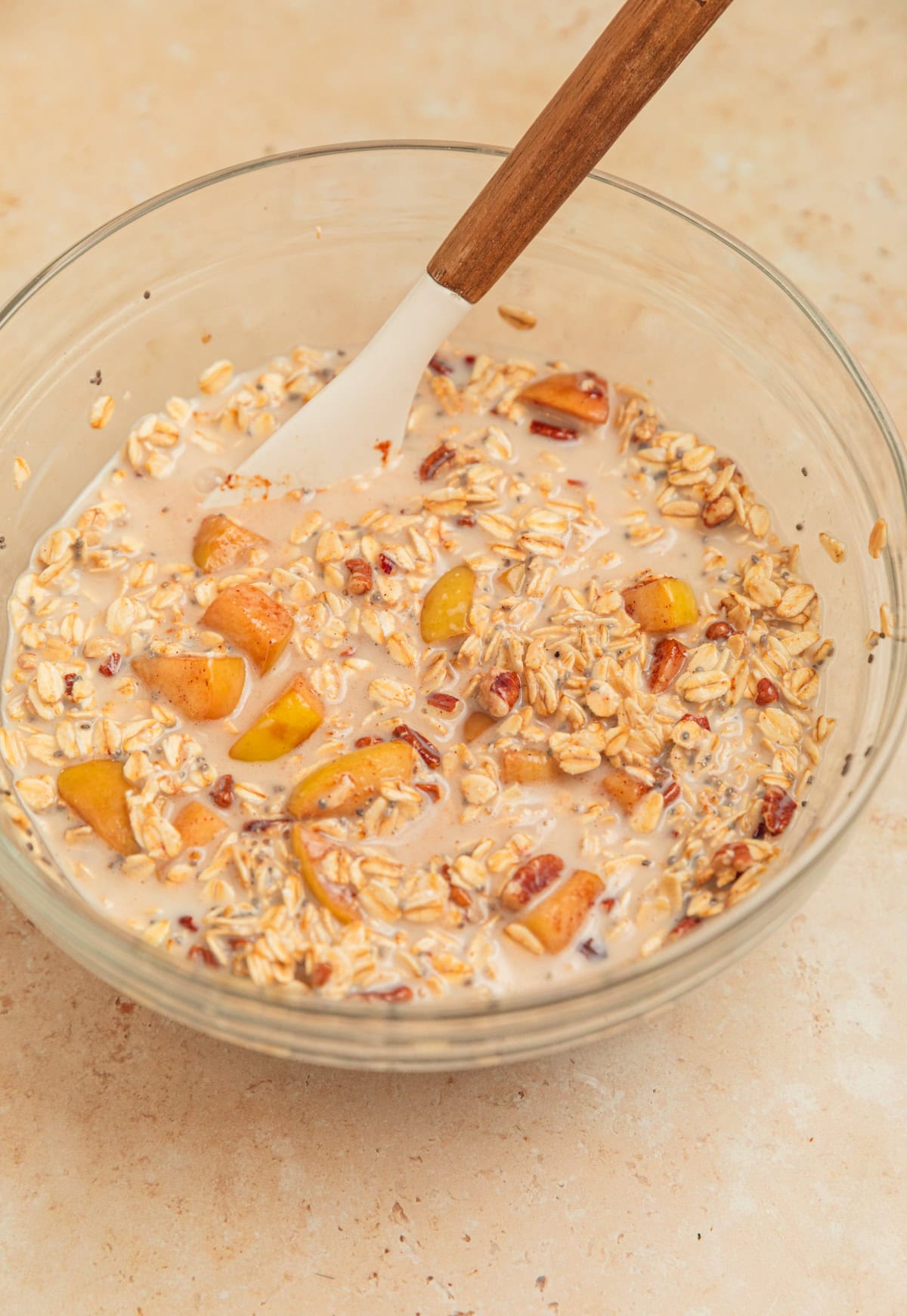 Apple overnight oatmeal mixture in bowl with spoon.