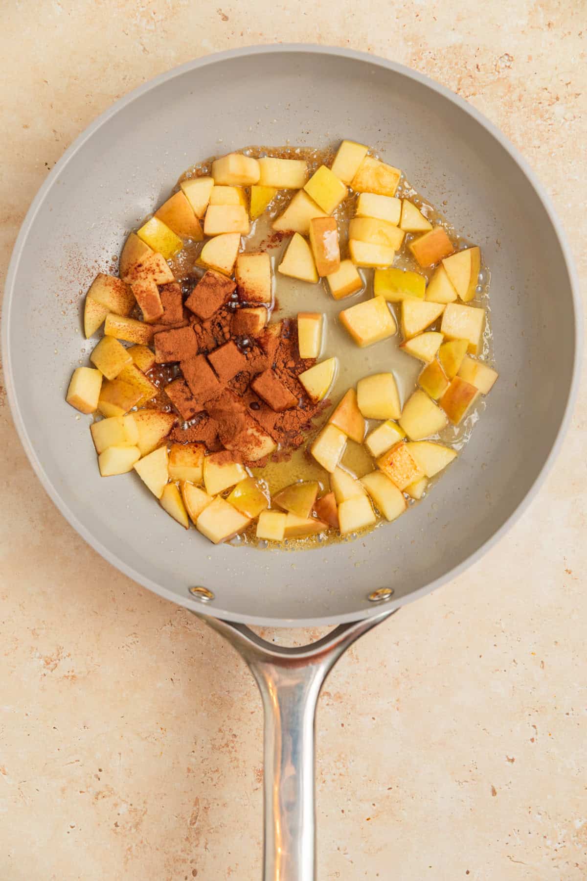 Softened apples in skillet with cinnamon, water and maple syrup.