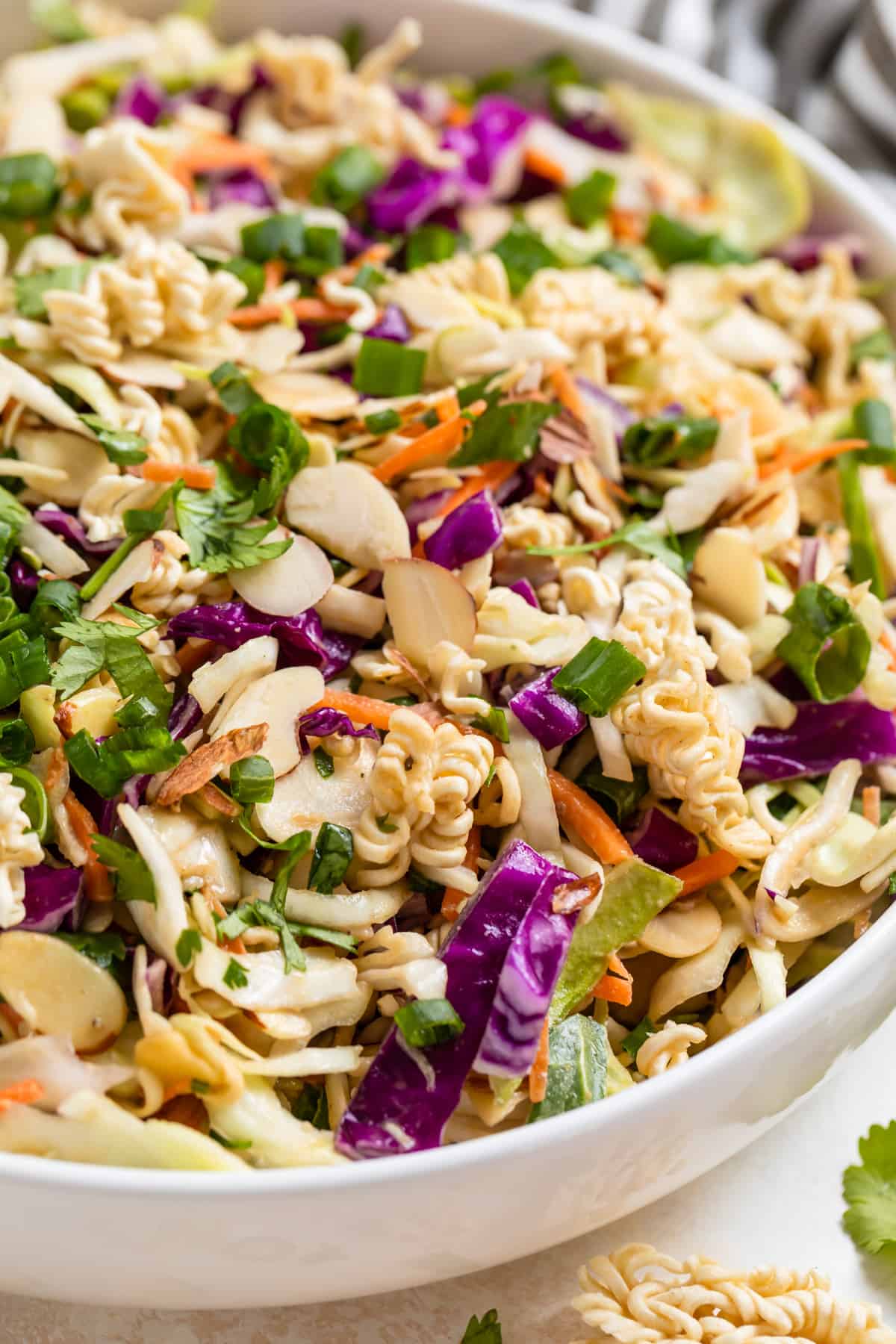 Ramen cabbage salad with peanut dressing topped with sliced almonds, cilantro and green onion.