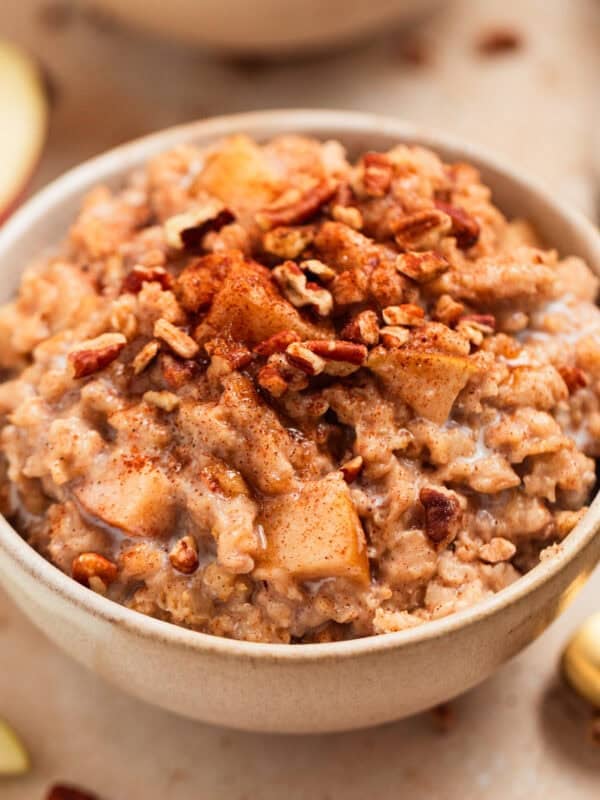 Bowl of apple cinnamon oatmeal topped with chopped pecans.