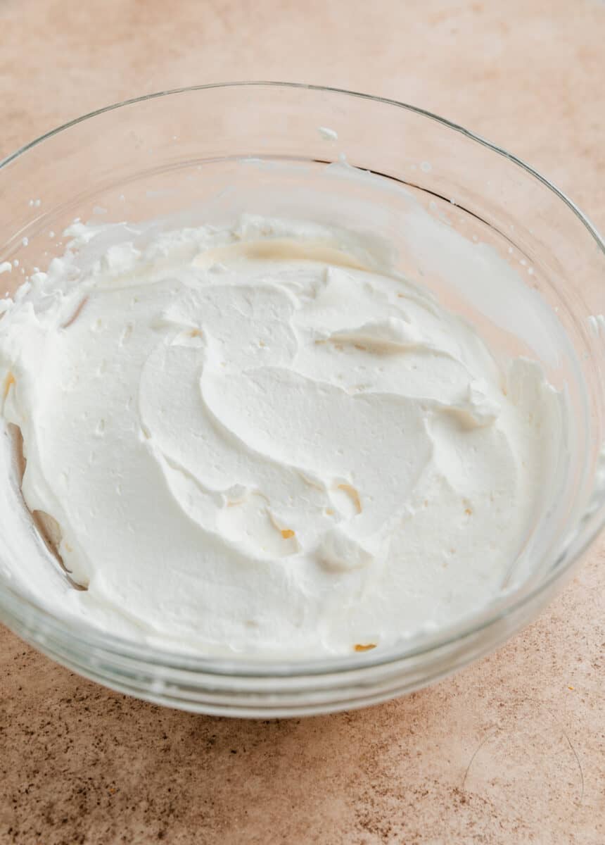 Whipped whipping cream in glass mixing bowl.