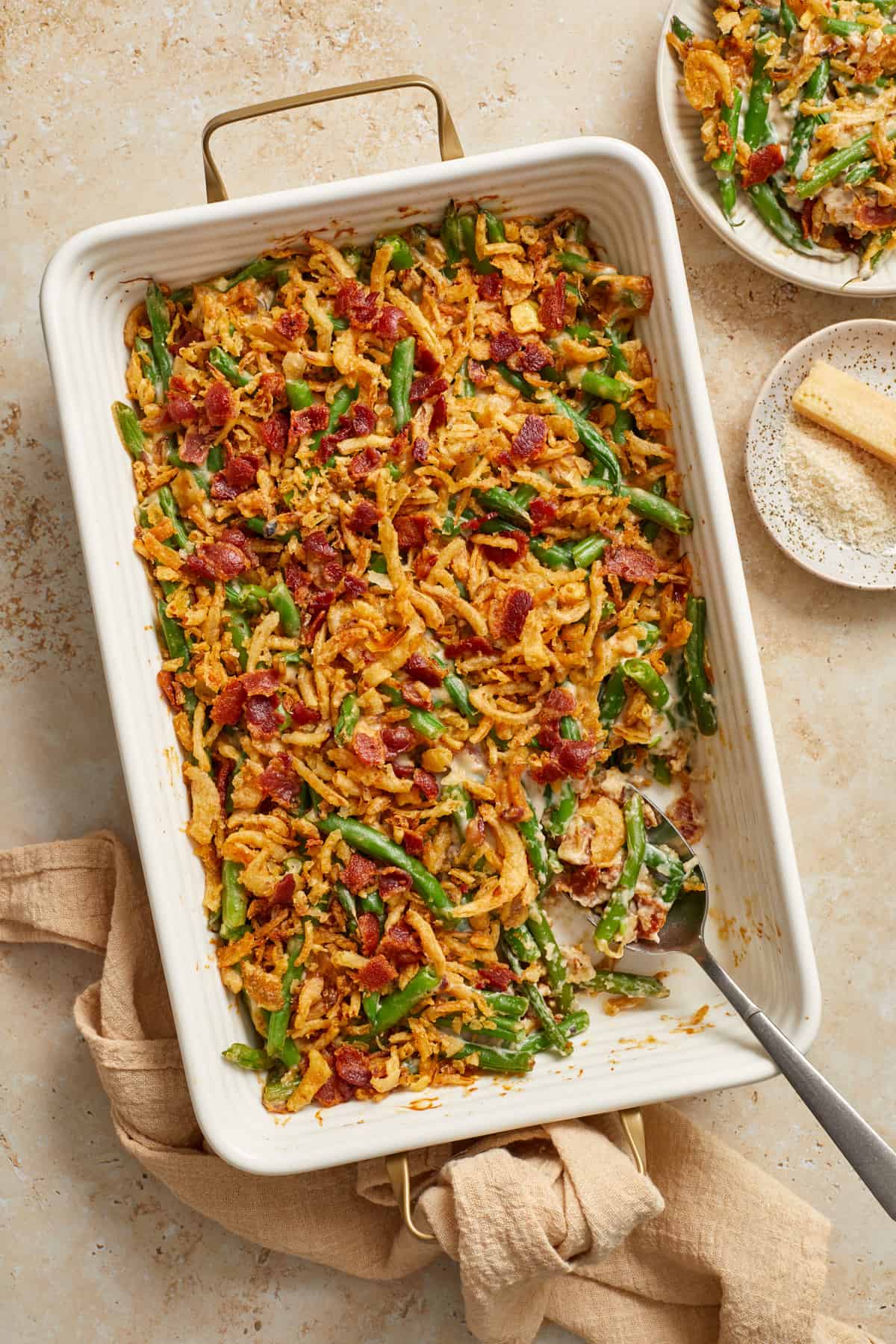 Dish with green bean casserole with bacon with serving spoon.