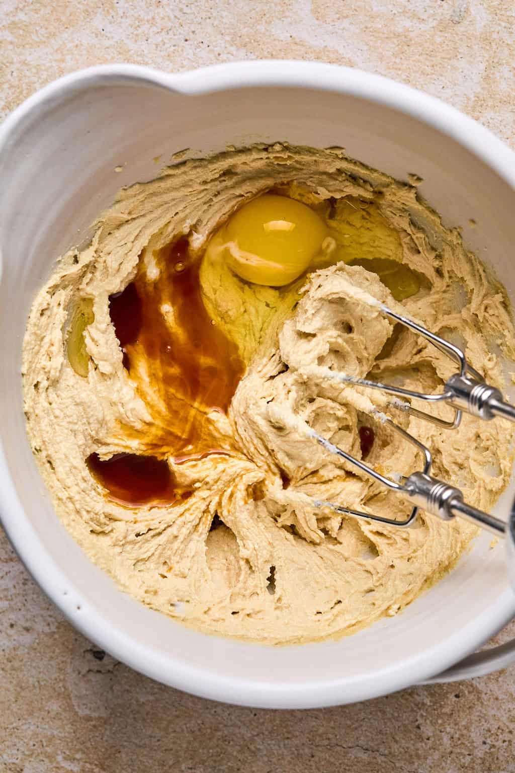 Egg and vanilla added to mixing bowl with creamed butter and sugar.