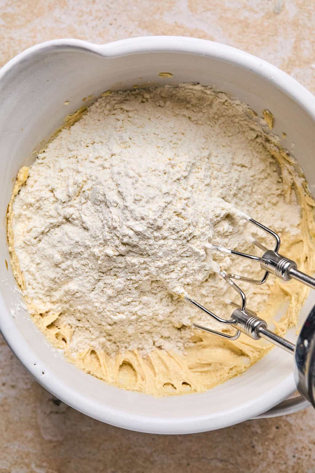 Flour mixture added to cookie dough wet ingredients in bowl before mixing.