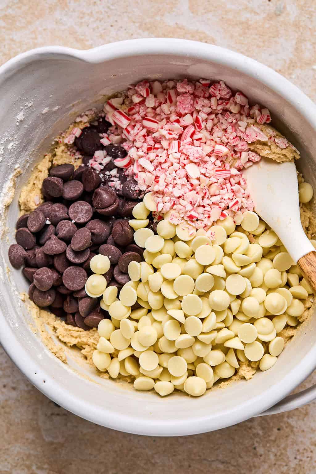 Crushed candy canes, white chocolate chips and dark chocolate chips in bowl before being mixed into dough.