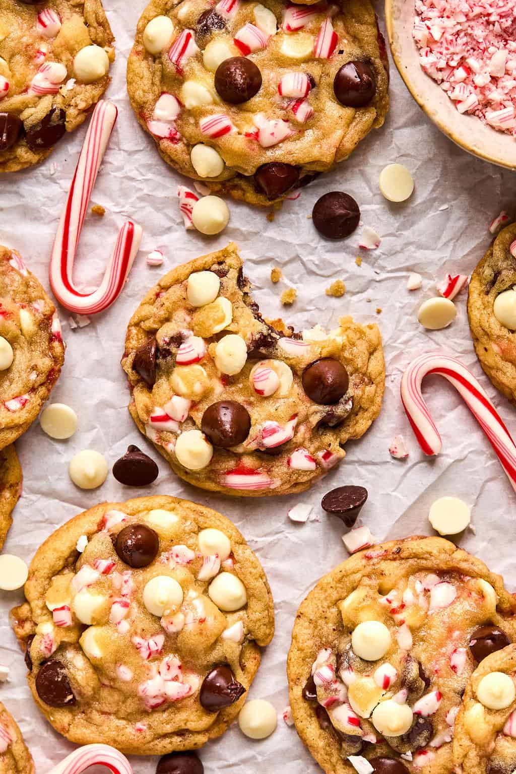 Overhead view of candy cane chocolate chip cookies with dark and white chocolate chips and candy canes surrounding.