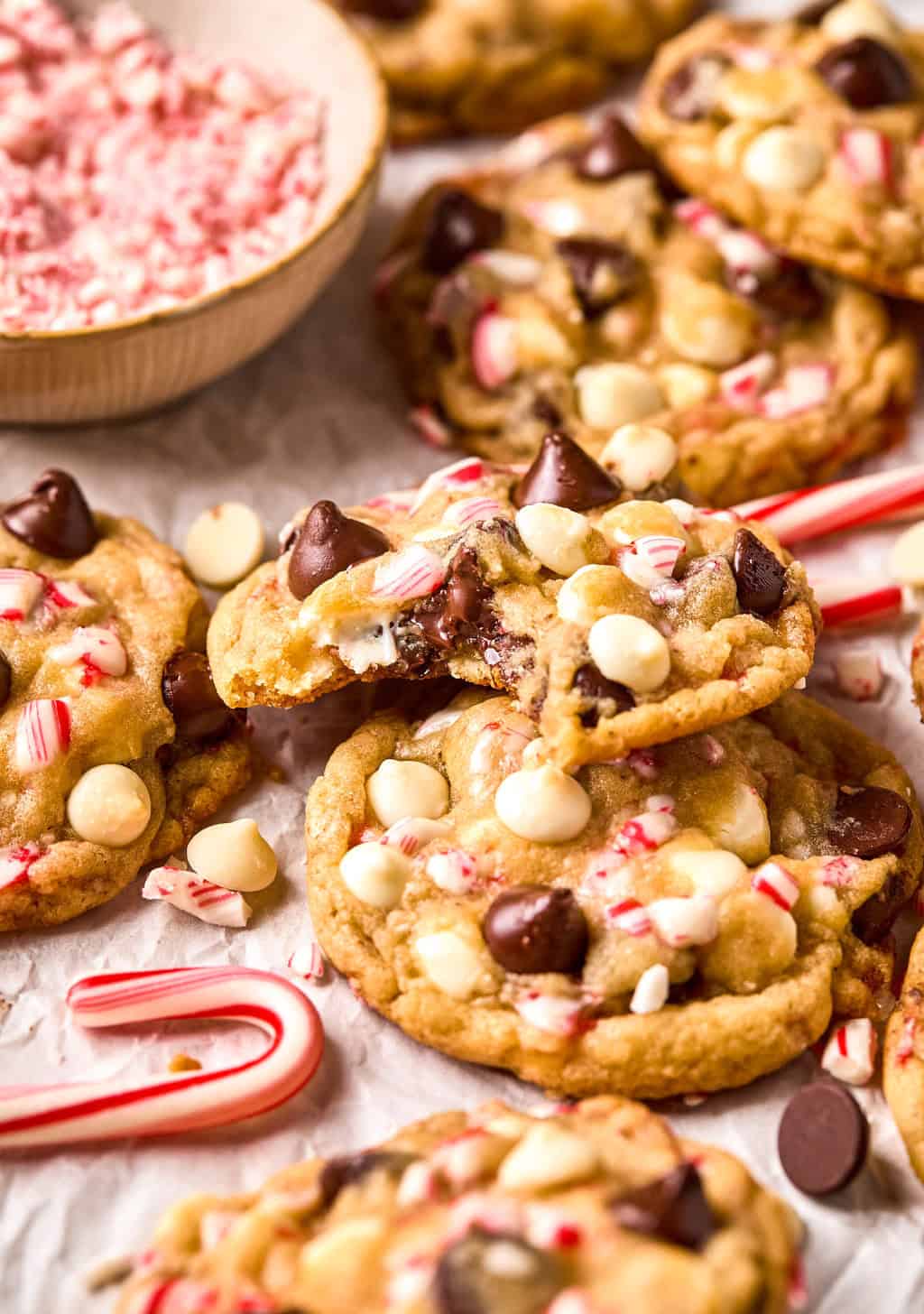 Peppermint chocolate chip cookies arranged on parchment with candy canes.