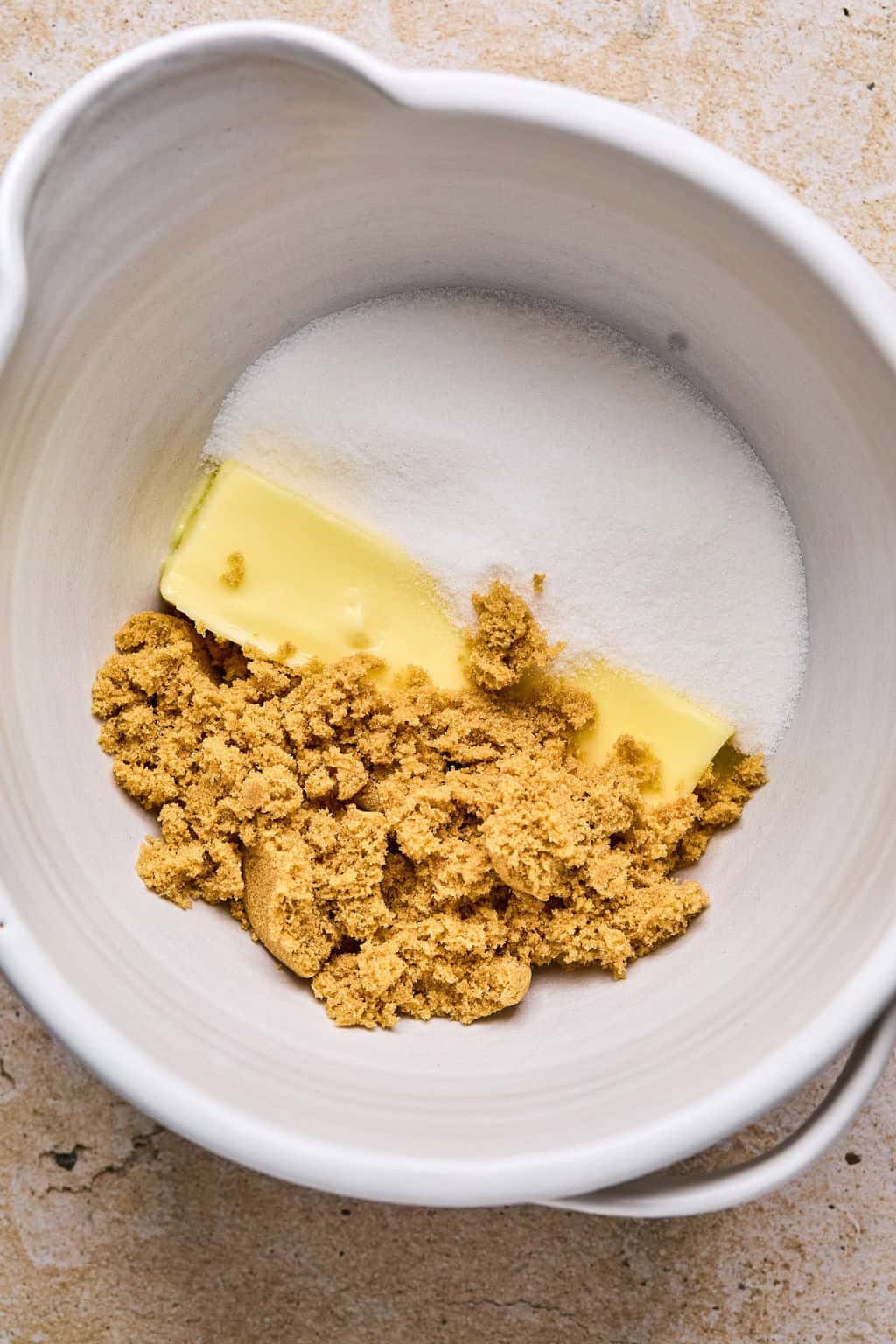 Butter, brown and white sugar in bowl before mixing.