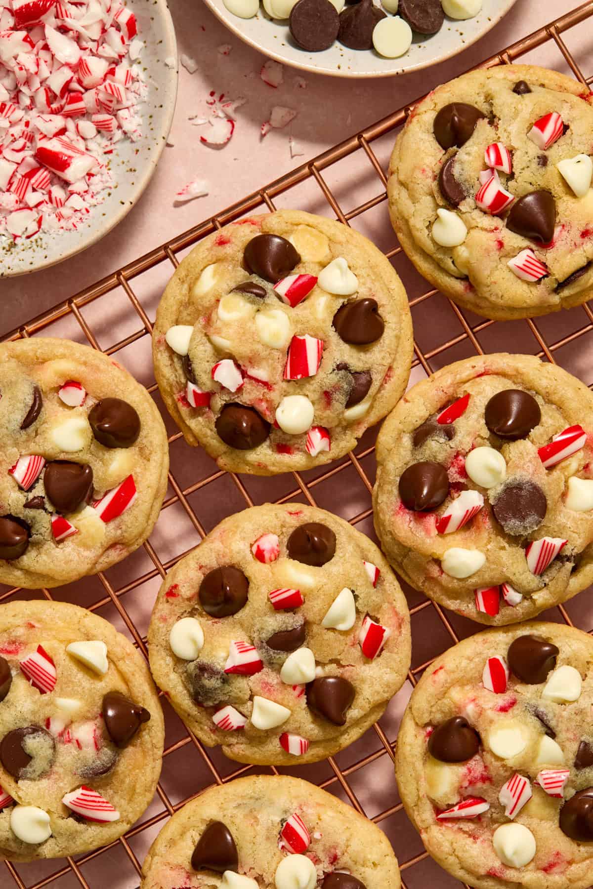 Cooling rack with candy cane chocolate chip cookies and bowl with chips and crushed candy canes.