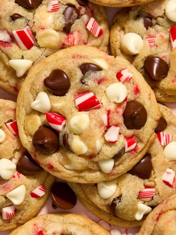 Peppermint chocolate chip cookies with white and dark chocolate chips and candy canes arranged on plate.