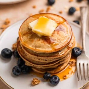 Stack of hot cakes made with bananas and oats topped with butter and maple syrup.