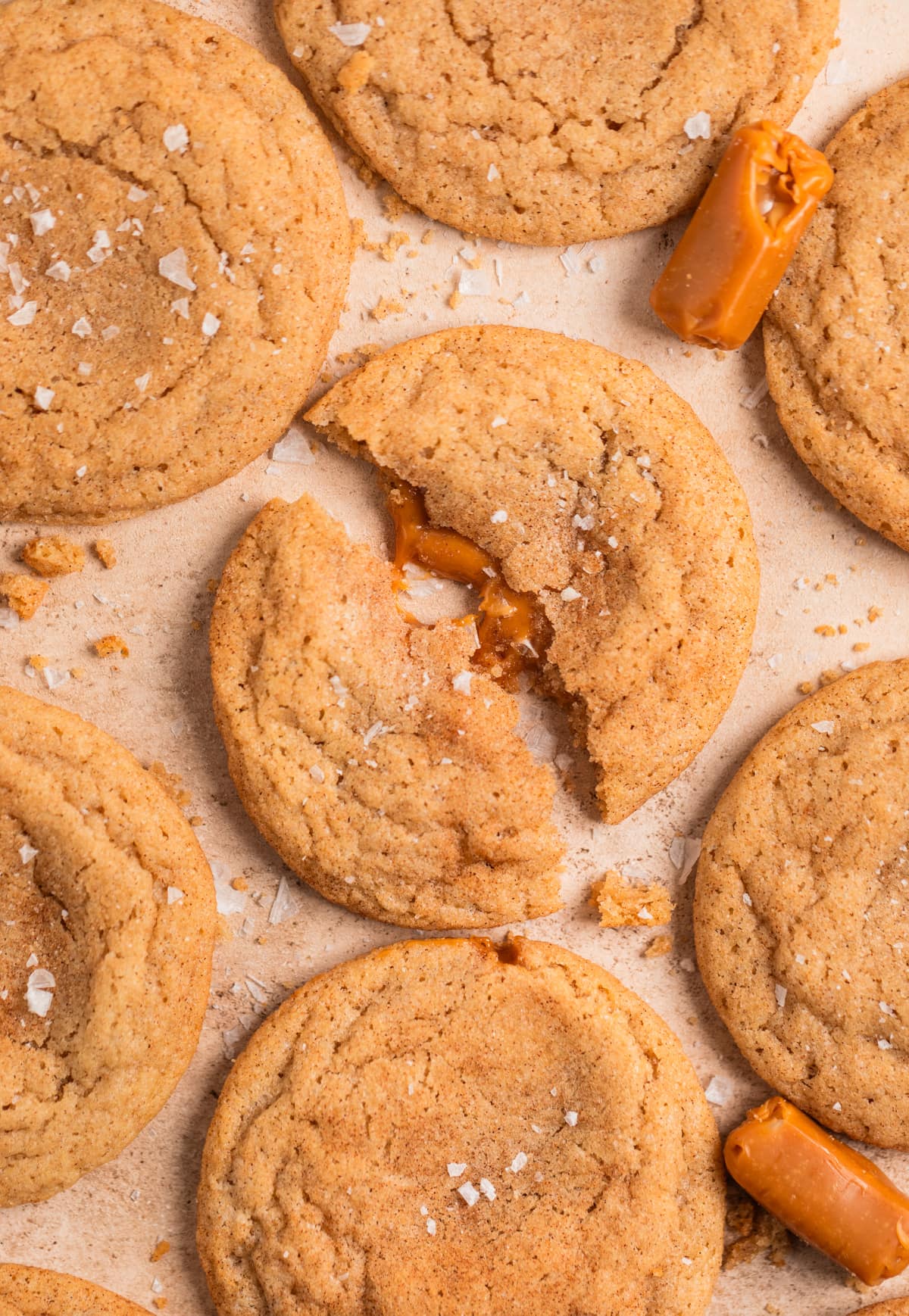 Caramel stuffed snickerdoodle cookies arranged on surface with sea salt sprinkled over top.