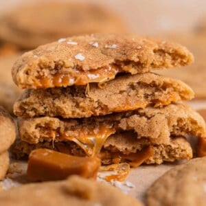 Stack of caramel filled cookies broken in half with caramel oozing out of the centers.