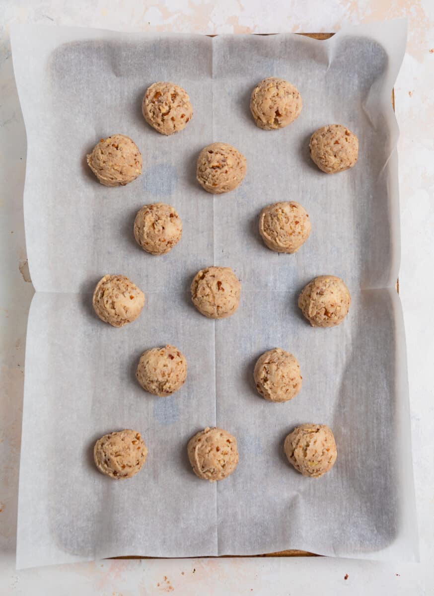 Scooped cookie dough on parchment lined cookie sheet.