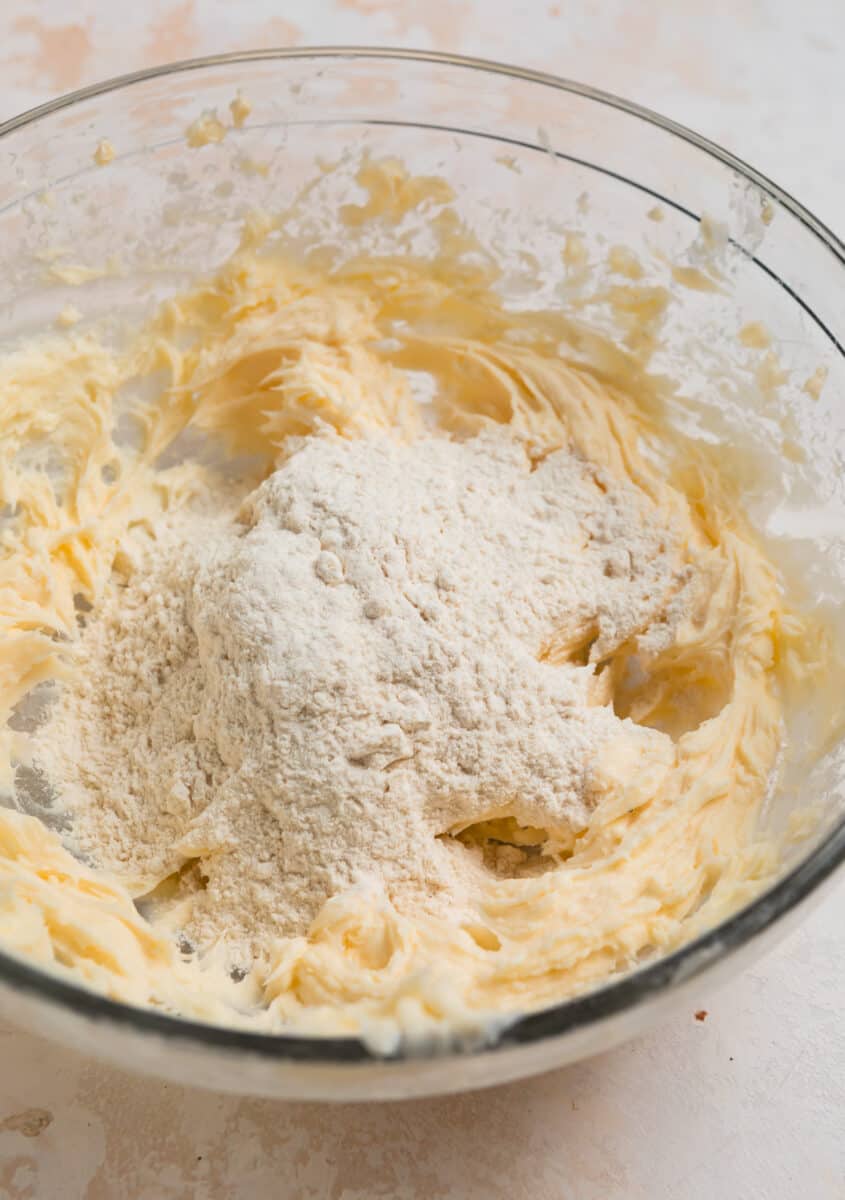 Flour added to butter mixture in a mixing bowl.