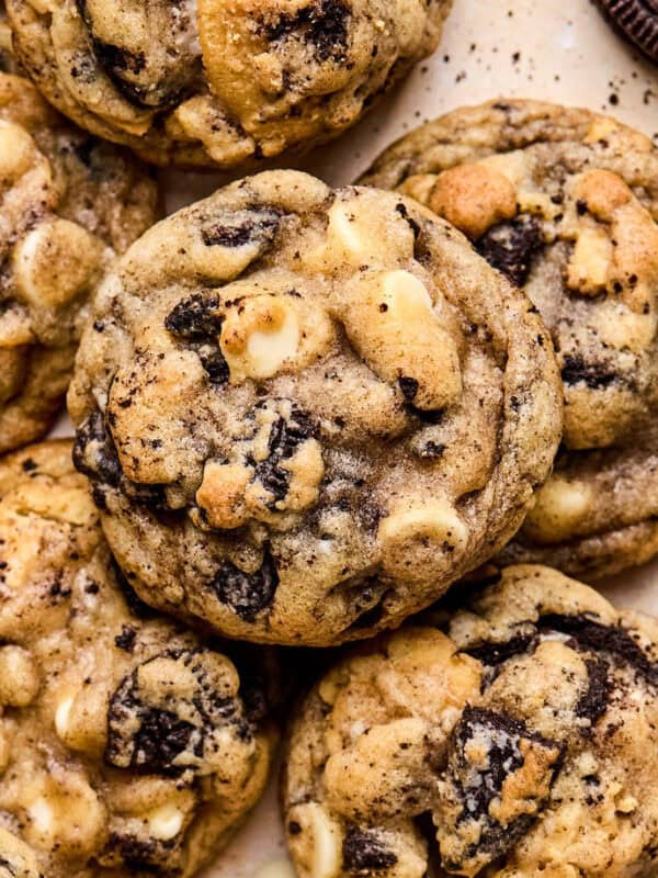 Oreo chocolate chip cookies arranged on surface with white chocolate chips and crumbs around them.