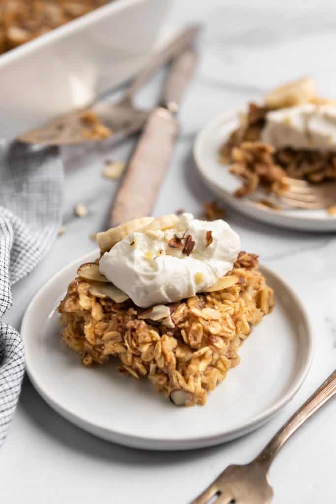 Banana Baked Oatmeal on a plate with yogurt and chopped nuts on top.