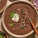 Black bean soup in bowl with spoon and toppings.