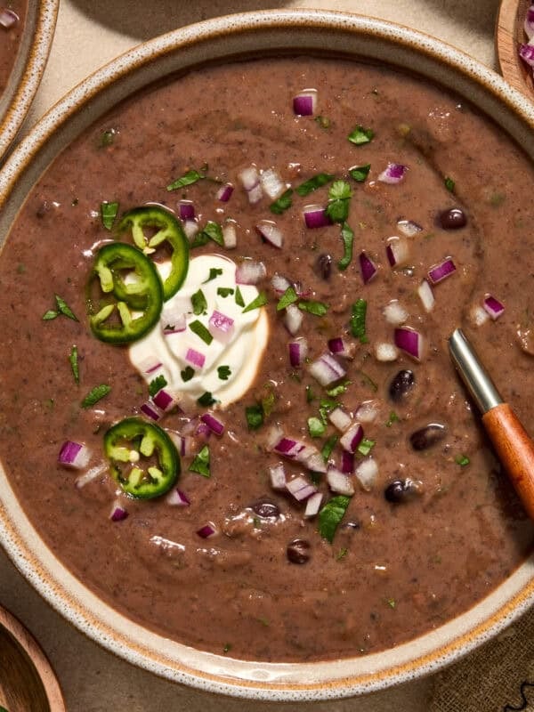 Black bean soup in bowl with spoon and toppings.